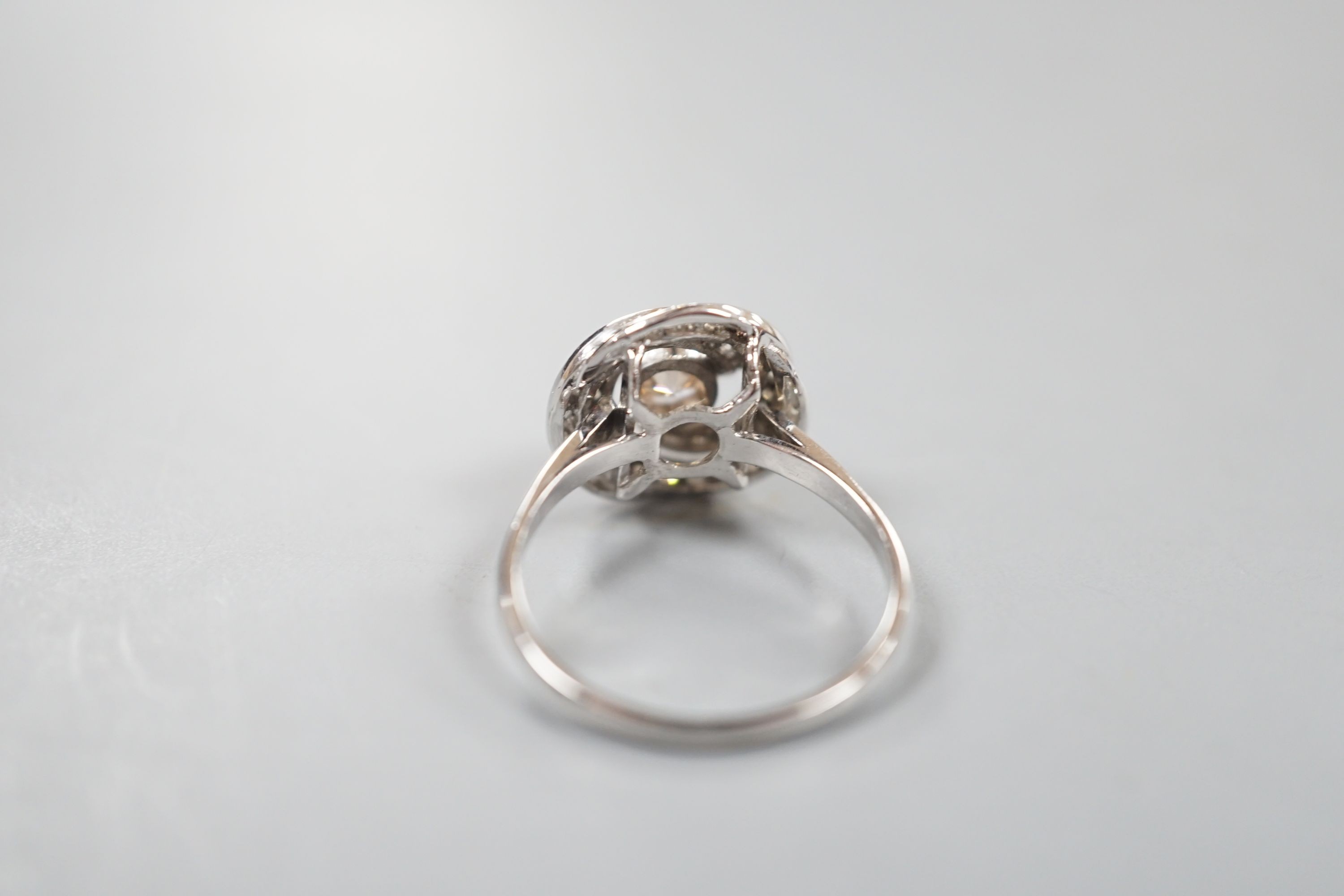 A French white metal(18ct poincon mark) and cognac coloured single stone diamond ring, with diamond set spiral cluster setting, size S, gross 5.5 grams.